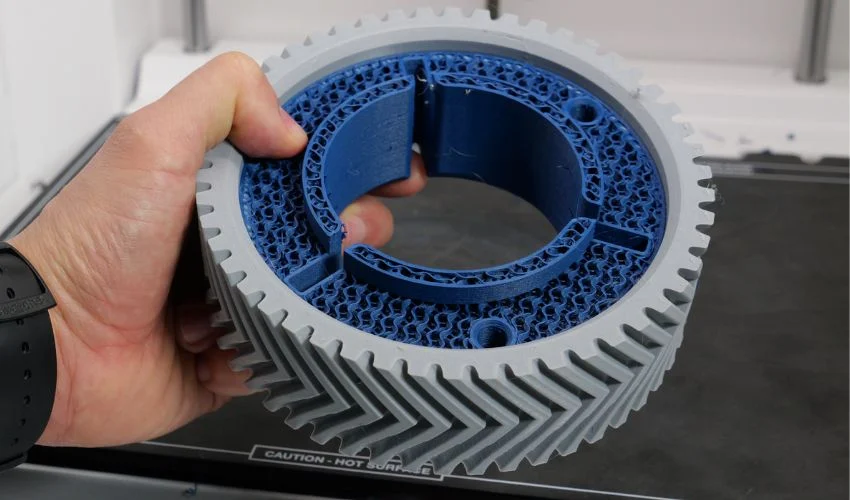 Multi-material filament 3D printed gear with gray outer body and blue internal structure